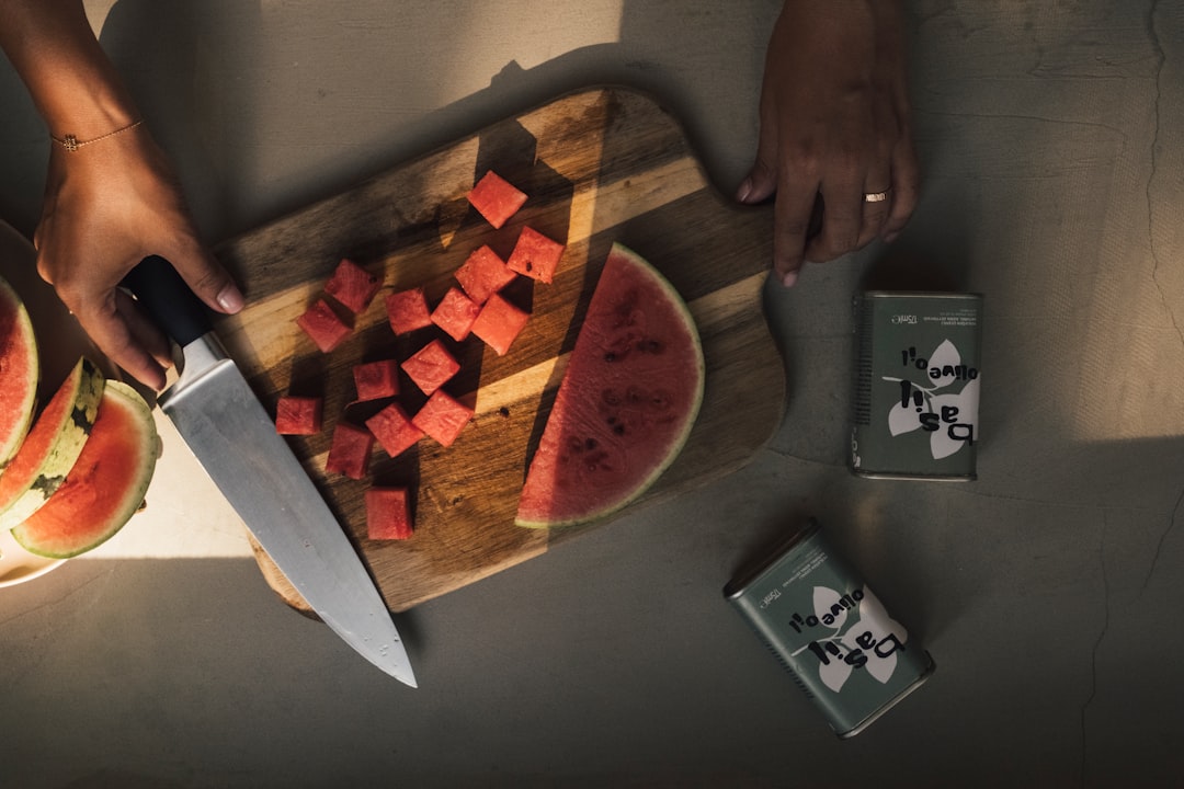Chopping watermelon on a wooden cutting board.